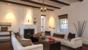 Una sala de estar con chimenea, sofás, una mesa de centro y una araña.