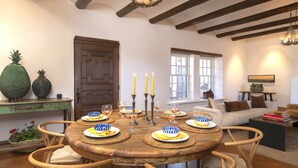 Un comedor con una mesa redonda de madera dispuesta para seis personas, rodeada de sillas de mimbre.