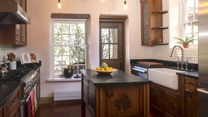 Una cocina con armarios de madera, estufa, pileta e iluminación colgante.