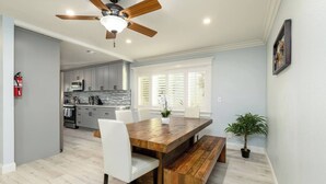 Una cocina moderna con armarios grises, una mesa de comedor de madera y un ventilador de techo.
