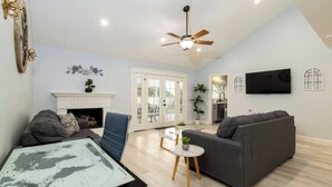 Una sala de estar moderna con chimenea, una mesa de comedor, un sofá y un televisor montado en la pared.