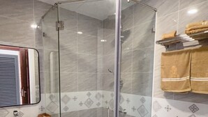 Un baño moderno con ducha de vidrio, inodoro blanco y lavamanos con espejo.