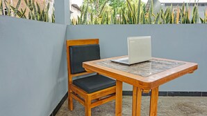 A wooden chair with a black cushion and a small wooden table with a laptop on it.