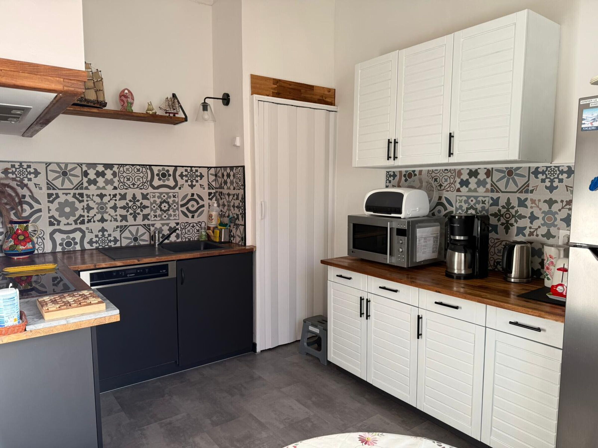 Una cocina compacta equipada con lavavajillas, microondas, cafetera y un refrigerador pequeño.
