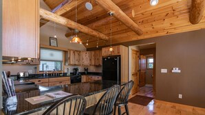 A spacious kitchen with wooden cabinets, a central island with bar stools, and a black refrigerator.
