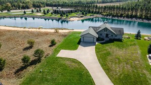 A house with a garage, driveway, and a view of a lake and golf course.