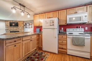 A kitchen with wooden cabinets, a refrigerator, a microwave, and a stove.