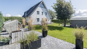 A modern house with a sloped roof, a paved driveway, and a well-maintained lawn. - Modern. Ruhig. Wiesenblick. Ringhoog Hüs Whg. 5 "weitblick" Objekt-id: Rhh/05 (Westerland)