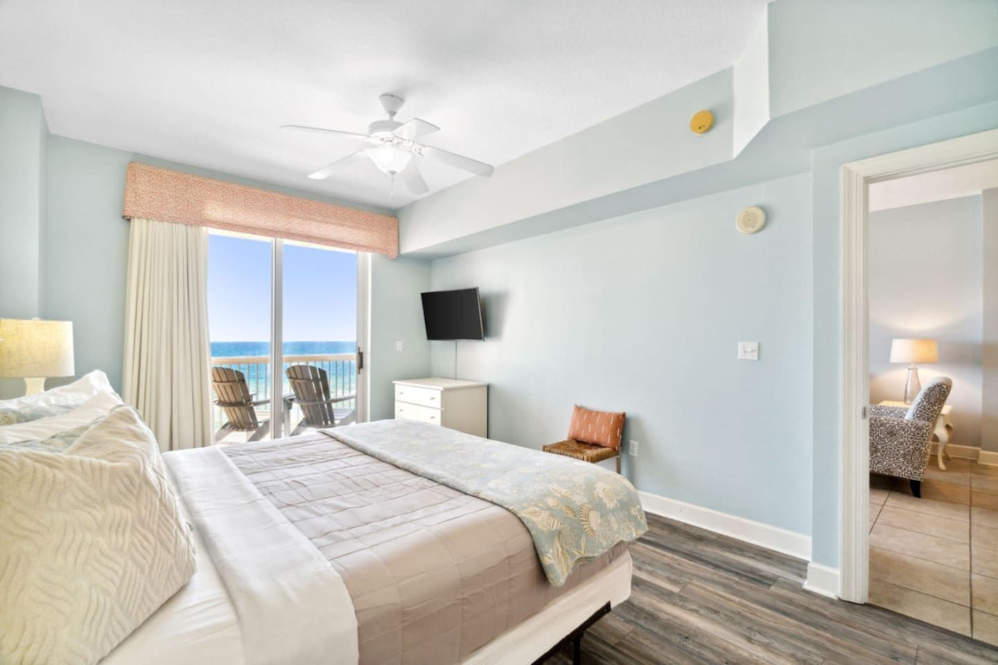 Une chambre d’hôtel avec un lit, une télévision, une chaise et une vue sur l’océan.