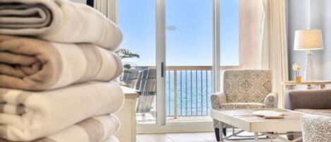 A hotel room with a balcony, a chair, a table, and a lamp.