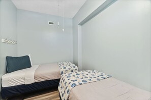 A small, single-bed room with a bed, a bedside table, and a wall-mounted light fixture. - Sunrise Resort Waterfront Beach and Pools Sleeps 8 (Panama City Beach)