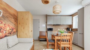 Un espacio habitable compacto con kitchenette, comedor y sofá.