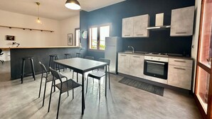 Eine moderne Küche mit Essbereich, ausgestattet mit einer großen Kochinsel, Barhocker und einem eingebauten Ofen.