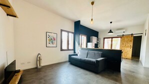 Ein modernes Wohnzimmer mit grauem Sofa, einer Holzbank und einem Flachbildfernseher.