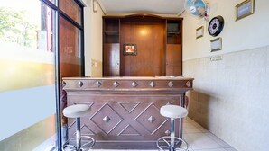 Een receptie met een houten balie, twee barkrukken, een klok en een ingelijste foto aan de muur.