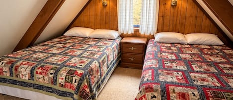 Un dormitorio con dos camas, paredes de madera, una ventana con cortinas y una mesita de noche.