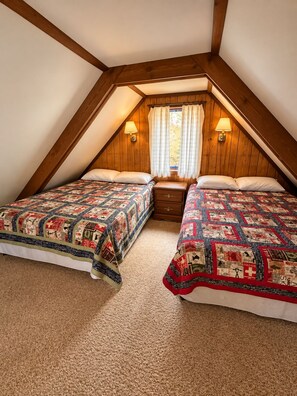 A bedroom with two beds, wooden walls, a window with curtains, and a nightstand.