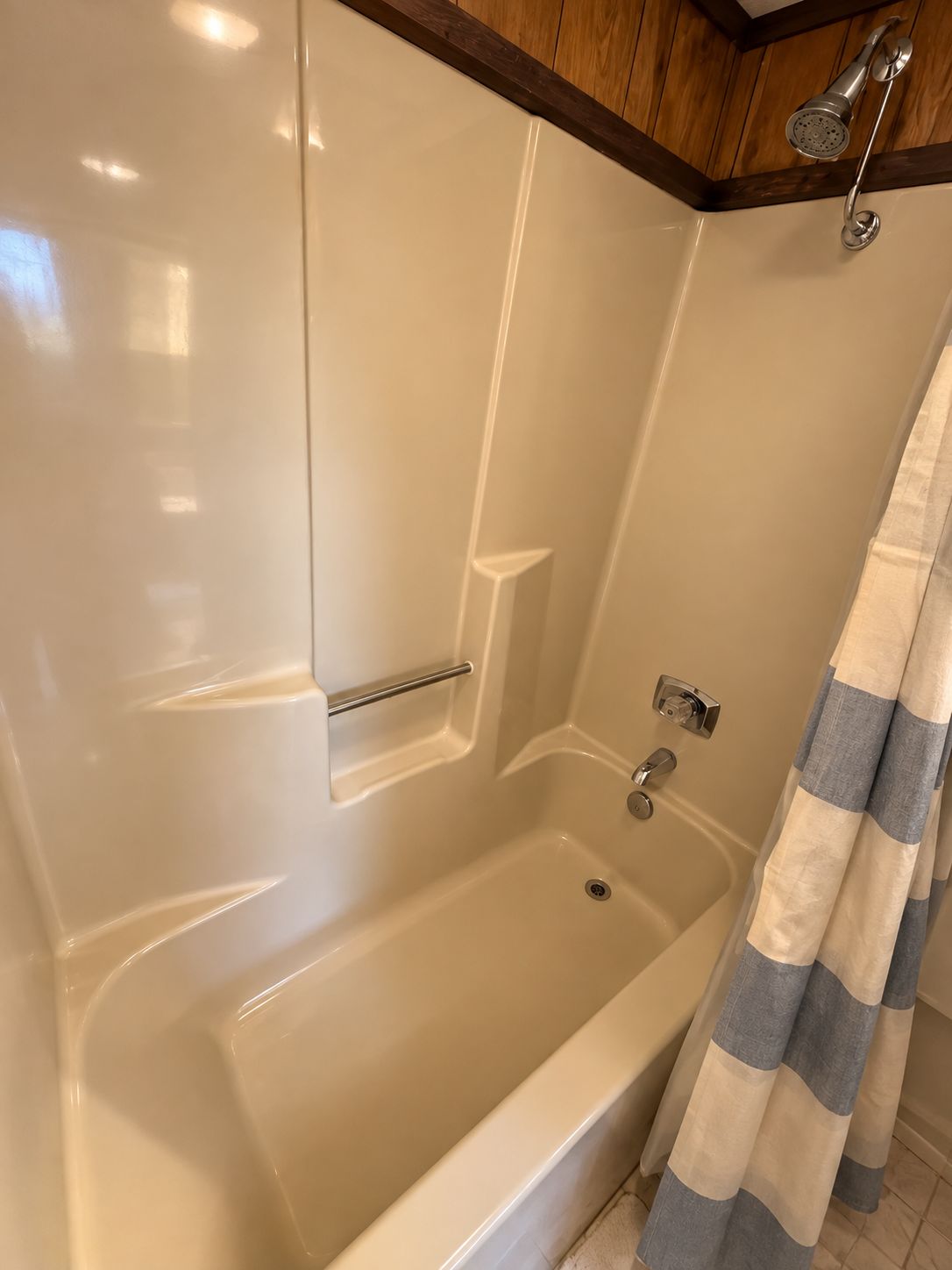 A bathroom with a bathtub, a showerhead, and a towel rack.