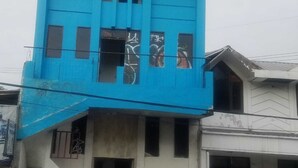 Un immeuble à plusieurs étages, doté d’une façade bleue, d’un escalier menant à l’entrée et d’une porte bien visible.