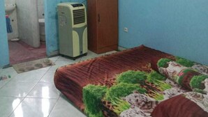 Une chambre avec un lit, un téléviseur posé sur un meuble, et une salle de bain visible à travers une porte ouverte.