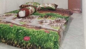 Une petite pièce, peu meublée, avec un lit, un téléviseur posé sur un meuble et un climatiseur fixé au mur.