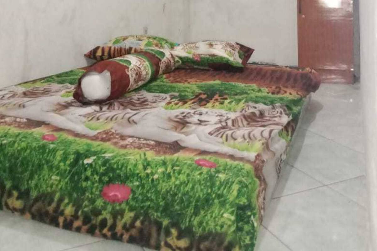 Ein kleiner, schlicht eingerichteter Raum mit einem Bett, einem Fernseher auf einem Schrank und einer Wandklimaanlage.