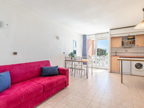 Apartamento moderno com sofá vermelho, área de refeições e cozinha com máquina de lavar.