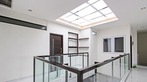 Un interno moderno con ringhiera in vetro, lucernario e pavimento in marmo.