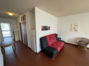 A room with a sofa, a small table, a refrigerator, and a chair. - Spacious 2-BR Apt in Saint-Cyprien, 400m to Beach, Pets Allowed (Saint-Cyprien)