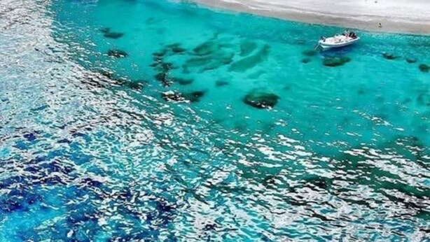 A coastal scene with clear turquoise waters, a sandy beach, and rocky cliffs with caves. - Holidays in Sardinia, apartment Arbatax (Arbatax)