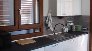 A kitchen with a wooden-framed window, a sink, and a cutting board. - Holidays in Sardinia, apartment Arbatax (Arbatax)