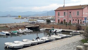 A harbor with boats docked, a bridge, and a pink building labeled "ARBATAX". - Holidays in Sardinia, apartment Arbatax (Arbatax)