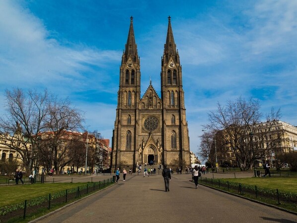A historic church with twin towers and a large rose window, surrounded by a park with pathways and benches. - Helen Hostel u Náměstí Míru (Prague)