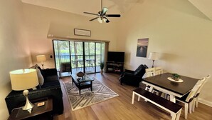 A spacious living room with a dining area, a ceiling fan, and a large sliding glass door leading to a balcony. - VDL 108 - Summer fun in the sun! (Saint Augustine)