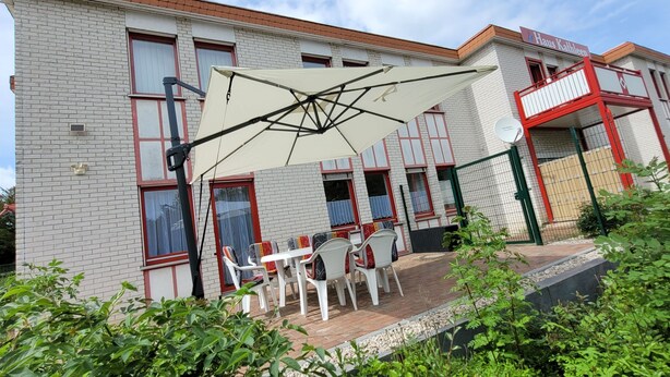 A building with a patio area featuring outdoor seating and a large umbrella.