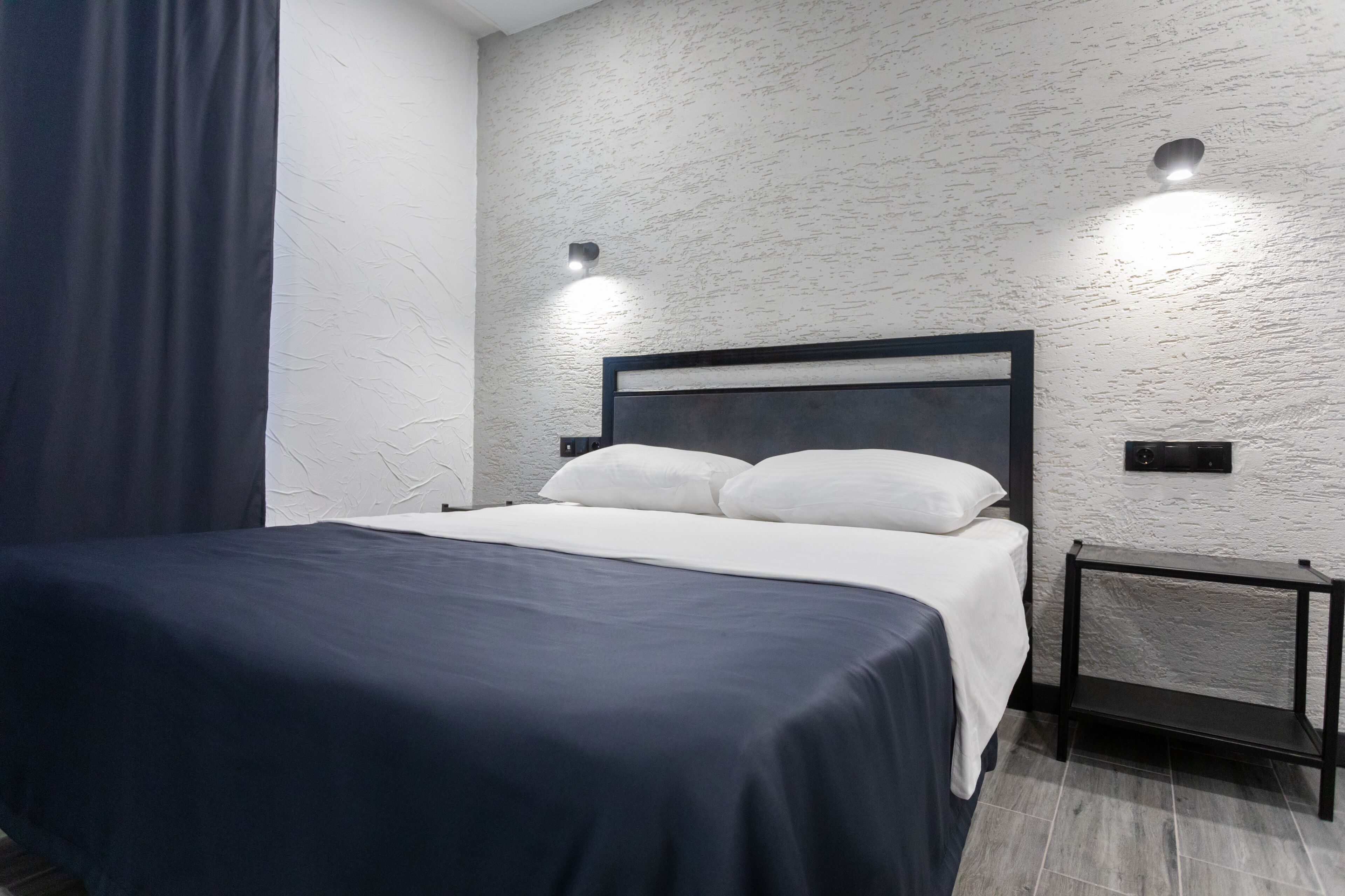 Une chambre à coucher moderne avec un grand lit, une table de chevet et un luminaire fixé au mur.