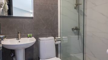 A modern bathroom with a glass-enclosed shower, a pedestal sink, and a toilet.