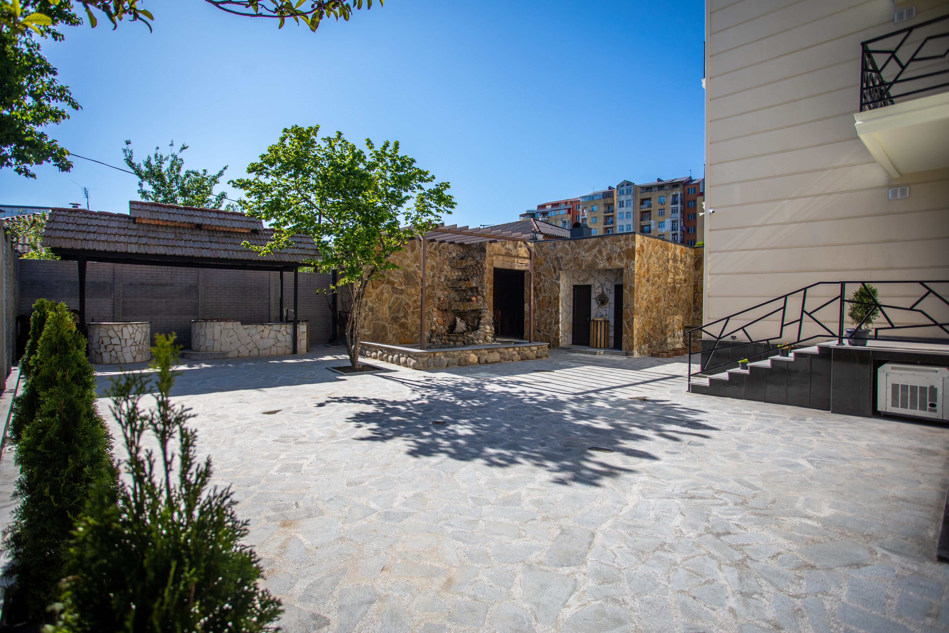 Un cortile con pavimento in pietra, un edificio in pietra con un ingresso e una scalinata che conduce a un piano superiore.