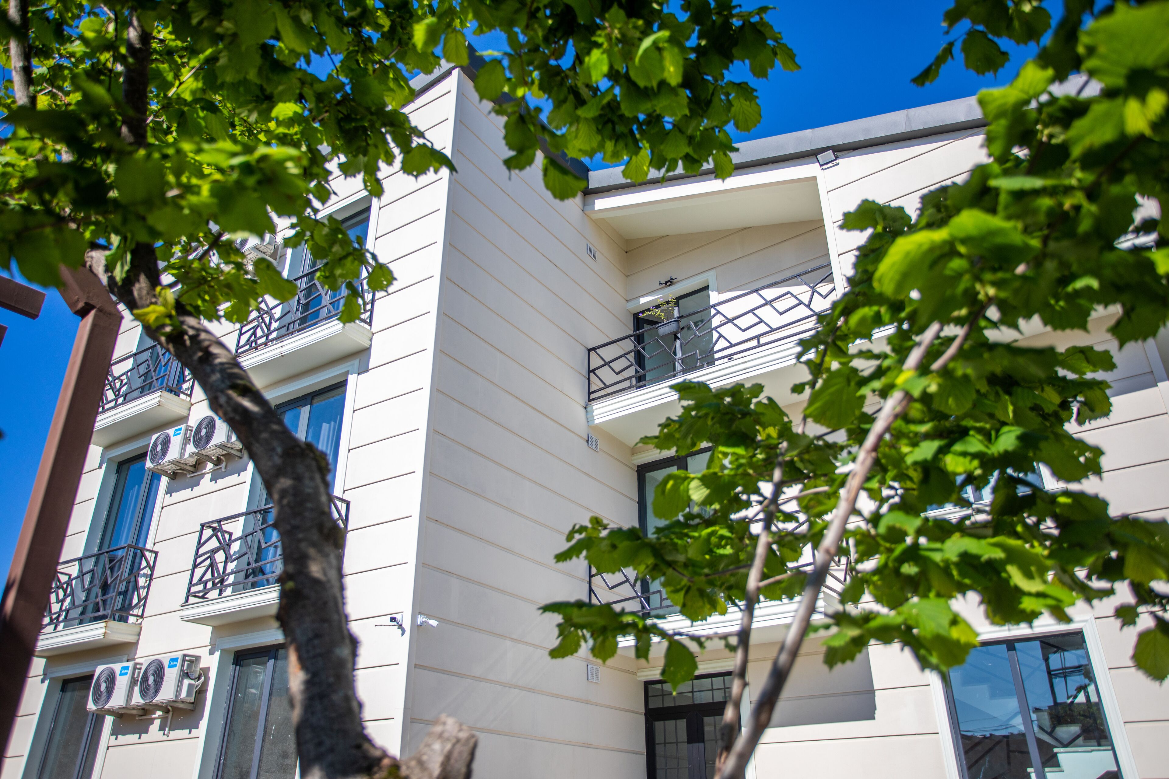 A multi-story building with balconies, air conditioning units, and a clear blue sky.