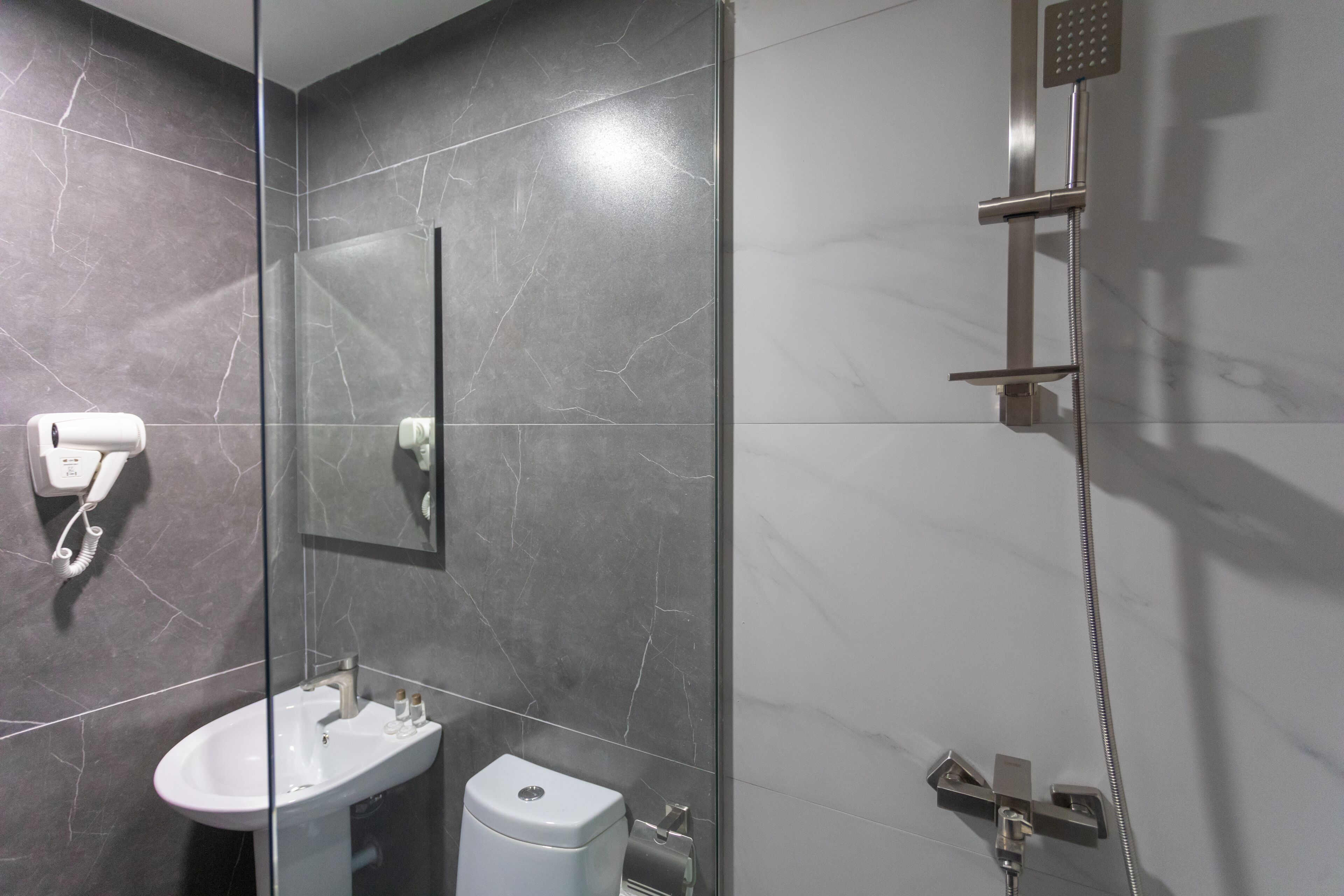 A modern bathroom with a glass partition, a white sink, a toilet, and a shower area.