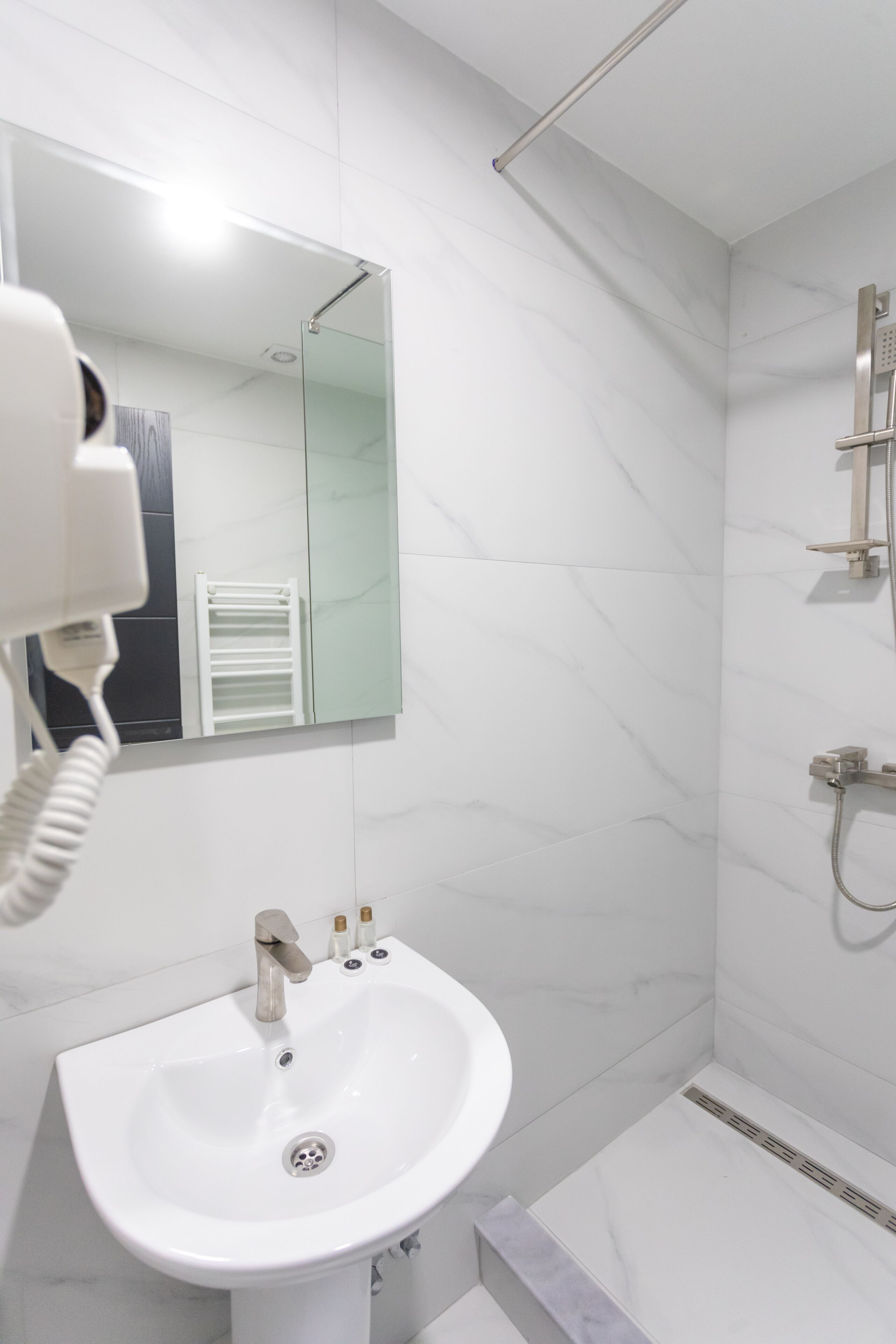 A bathroom with a white sink, a mirror, and a shower.