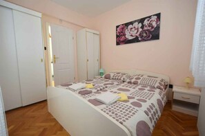 A bedroom with a bed, a nightstand, a lamp, a wardrobe, and a painting on the wall.