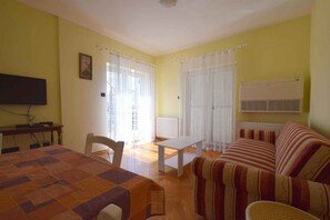 A room with a bed, a sofa, a dining table, and a TV. - Holiday apartment with balcony and two bedrooms (Milčetići)
