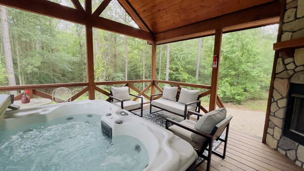 Un espace avec un jacuzzi, des sièges et une cheminée en pierre.