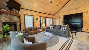 Un salon chaleureux avec une cheminée en pierre, des murs en bois et un grand téléviseur à écran plat.