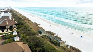 Une propriété située sur la côte, avec une plage, un escalier en bois et une vue sur l’océan.