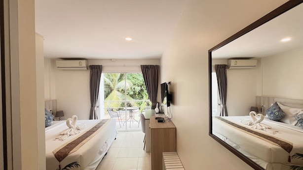 A hotel room with two beds, a TV, a desk, and a balcony with a view of greenery. - Mystays Phuket (Ko Kaeo)