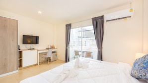 A hotel room with a bed, a desk, a chair, a TV, and a balcony with a view. - Mystays Phuket (Ko Kaeo)