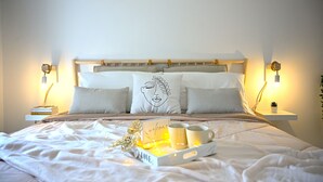 A neatly made bed with a tray of mugs and a card, bedside lamps, and a wall-mounted plant. - Holiday home in historical center a few minutes from the sea.  (Treglio)
