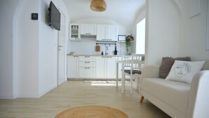 A modern kitchen with white cabinets, a dining area with a white table and chairs, and a living room with a white sofa and a woven rug. - Holiday home in historical center a few minutes from the sea.  (Treglio)